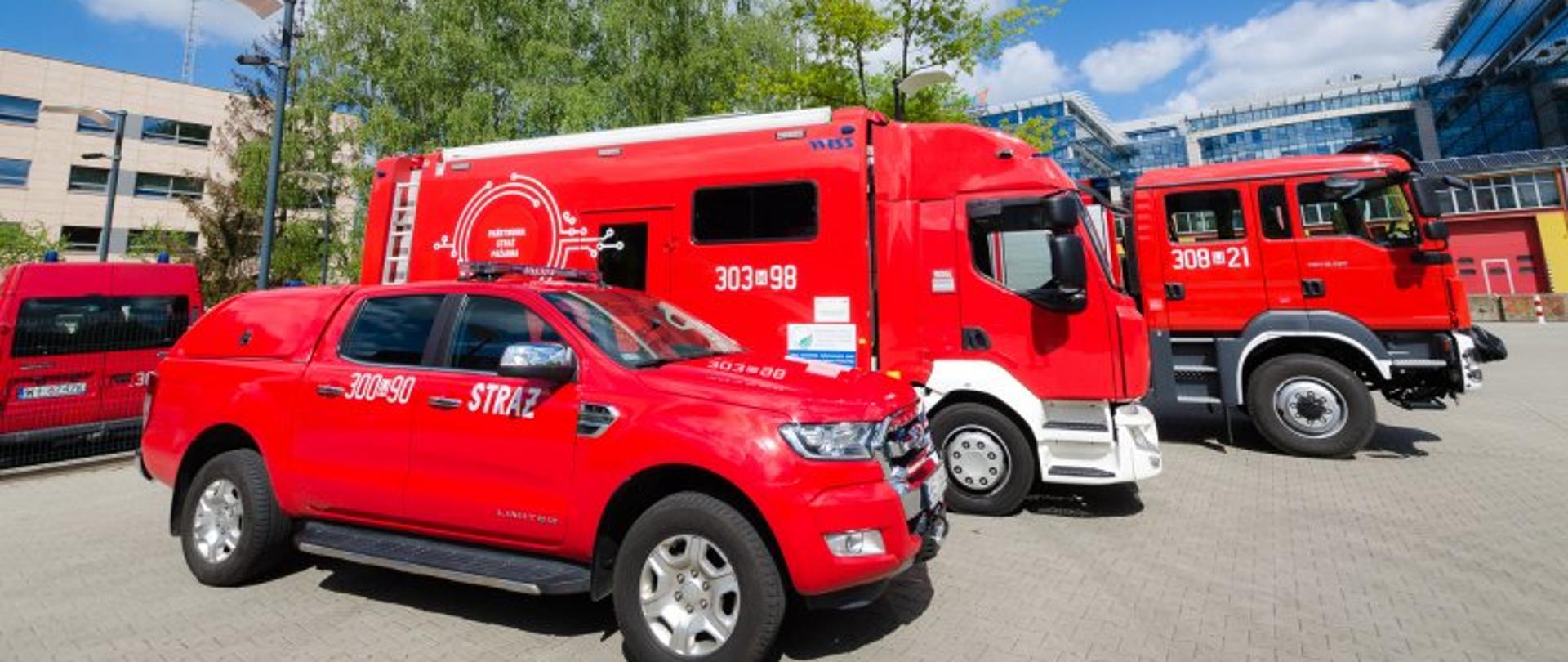 W ramach projektów unijnych PSP pozyskuje kolejne potężne środki – na zdjęciu trzy samochody strażackie. W tle garaże strażackie.