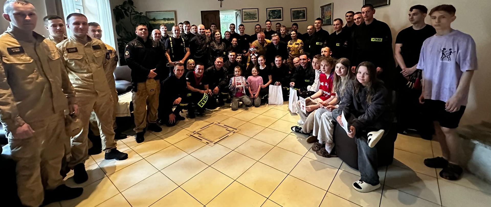 Pamiątkowe zdjęcie grupowe wychowanków Domu Dziecka wraz z wychowawcami i przybyłymi w odwiedziny strażakami