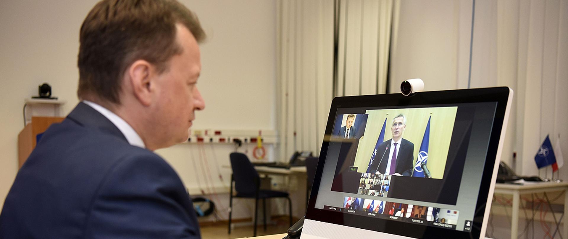 Minister Mariusz Błaszczak bierze udział telekonferencji Rady Północnoatlantyckiej. Na ekranie komputera Sekretarz Generalny NATO Jens Stoltenberg