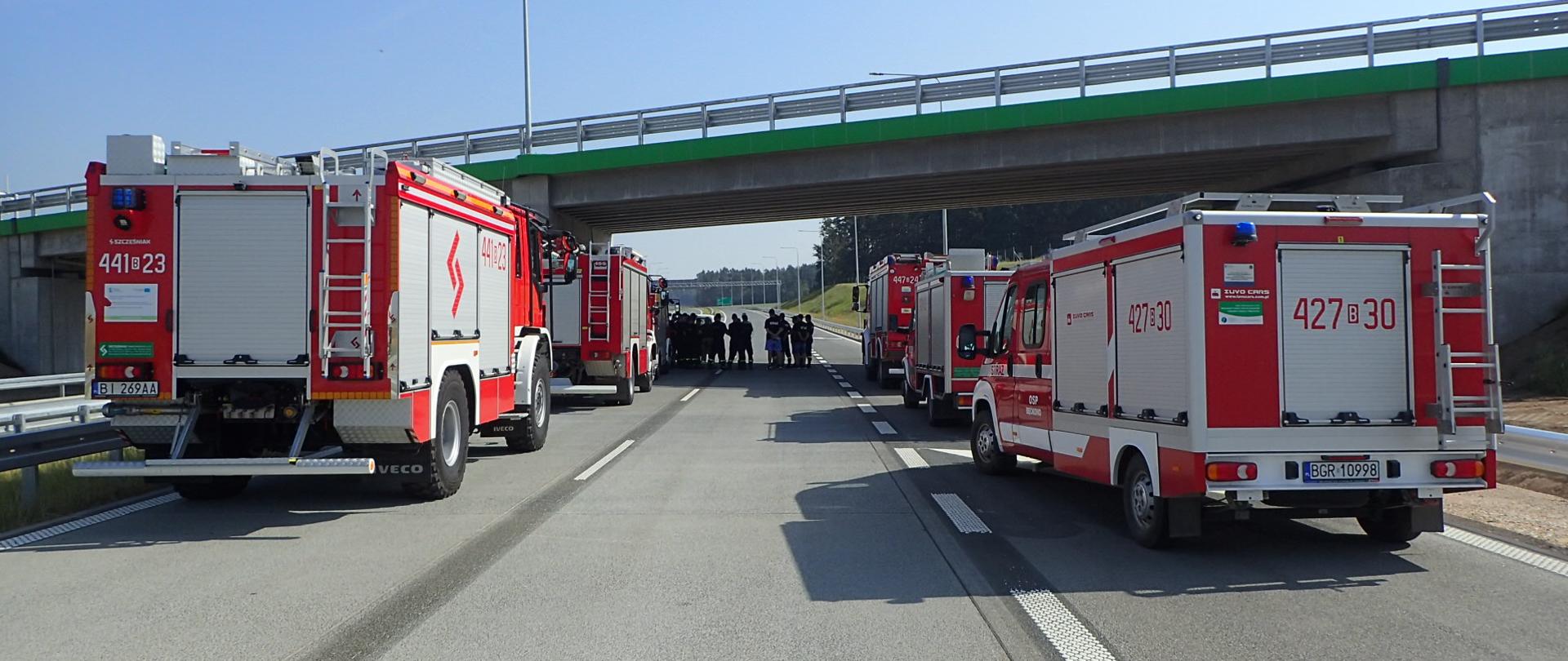 Pojazdy straży pożarnej stoją na drodze w trakcie ćwiczeń