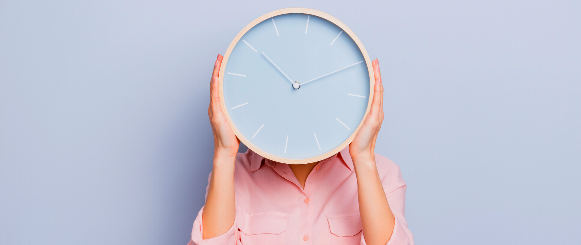 Kobieta trzymająca przed sobą duży okrągły zegar. Zegar wyświetla godzinę 10.10.