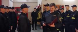 Uroczysta zbiórka strażaków. Komendant Powiatowy wręcza akt mianowania na stanowisko zastępcy dowódcy zmiany asp. Marcinowi Sadowskiemu 