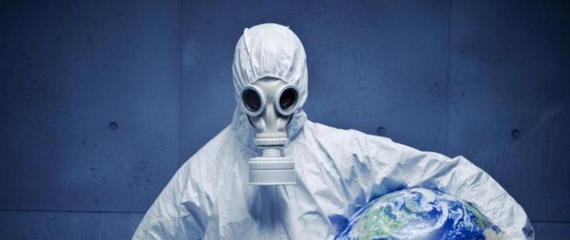 Człowiek w kombinezonie z kulą ziemska pod pachą