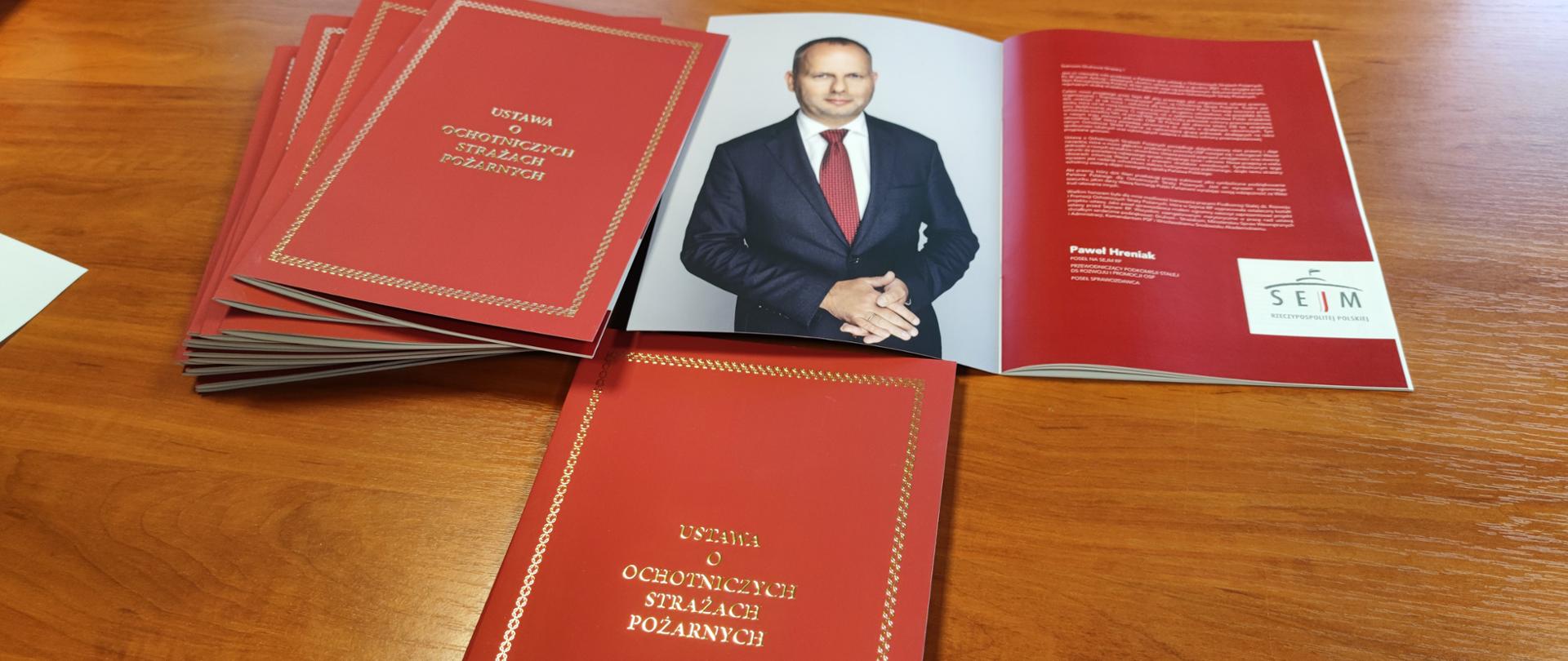 na zdjęciu widać pamiątkowe wydania ustawy o ochotniczych strażach pożarnych, ze zdjęciem posła Pawła Hreniaka