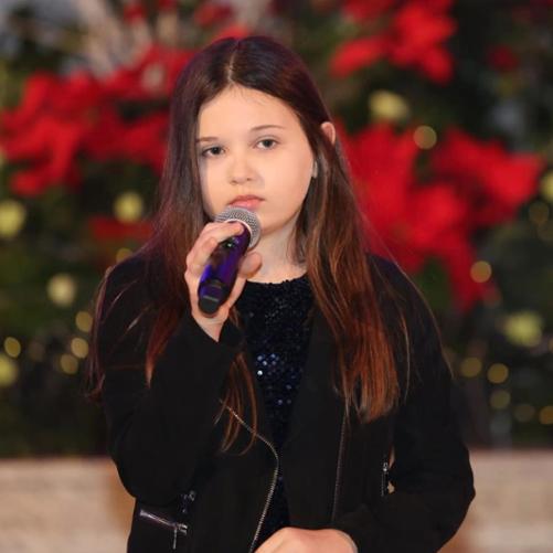 Lena Ptaszyńska z mikrofonem śpiewająca kolędę na konkursie.