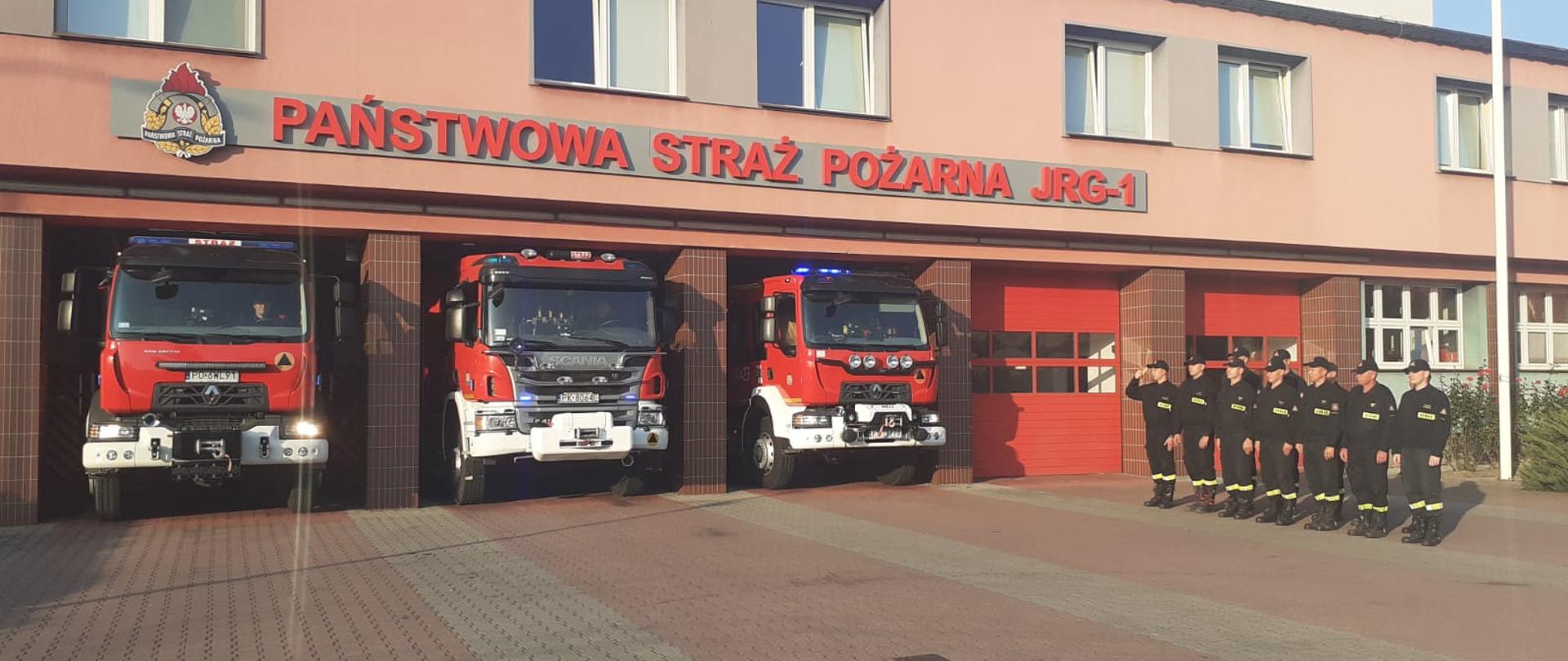 Strażacy na tle jednostki ratowniczo gaśniczej.