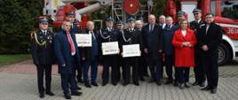 Na zdjęciu na tle samochodu strażackiego komendanci oraz parlamentarzyści wraz z druhami OSP którzy otrzymali promesy