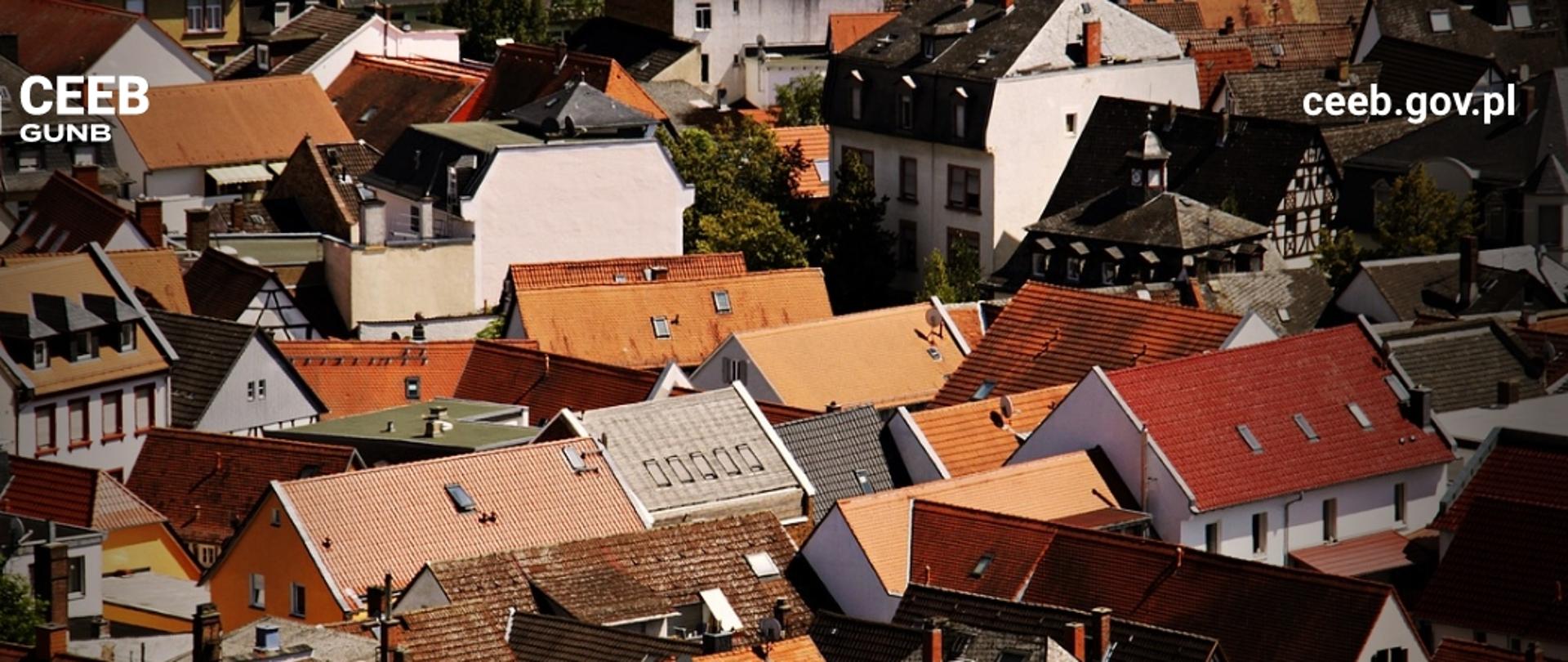 Widok z lotu ptaka na gęsto zabudowaną dzielnicę mieszkalną z różnorodnymi dachami; w rogu widoczne logo CEEB GUNB i adres strony ceeb.gov.pl.