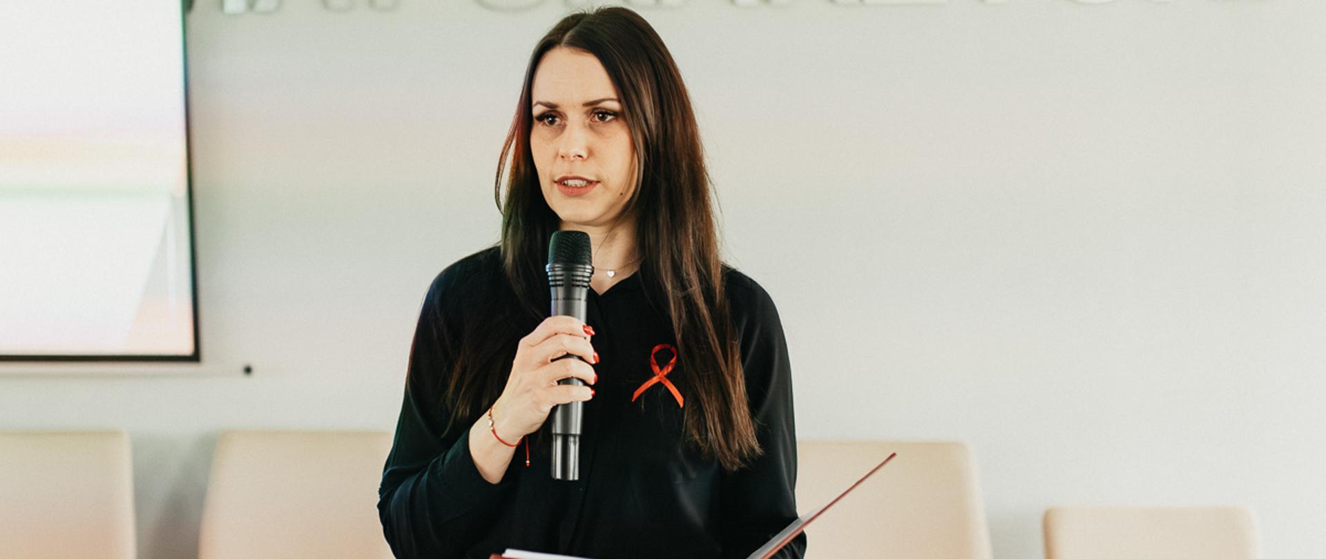 Pracownik PSSE przemawiający do zebranych na sali uczestników.