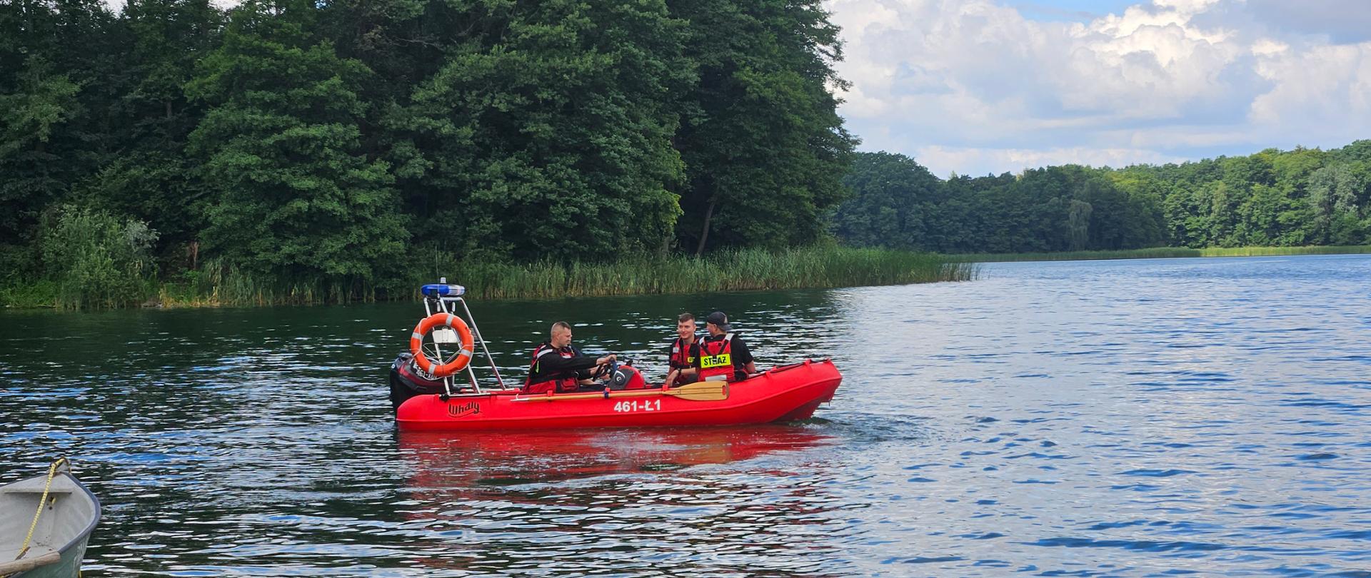 Strażacy płyną łodzią ratowniczą.