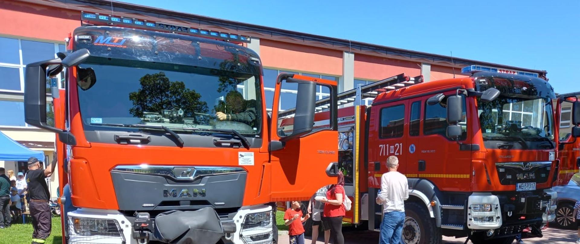 Strażacy Jednostki Ratowniczo – Gaśniczej na festynie rodzinnym pokazują uczestnikom samochody gaśnicze.