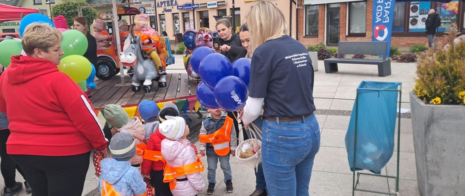 Inspektor WIORiN rozdaje gadżety promujące PIORiN dzieciom uczestniczącym w obchodach Dnia Pszczół na kazimierskim rynku