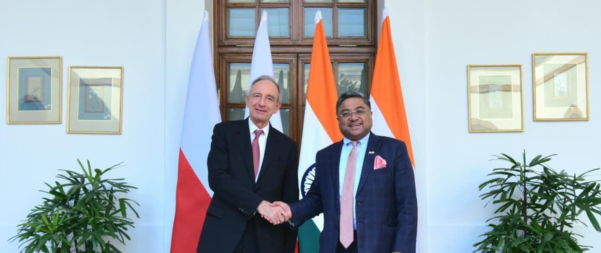 Minister Władysław Teofil Bartoszewski shakes hands with his Indian counterpart Sibi George against the background of the flags of Poland and India