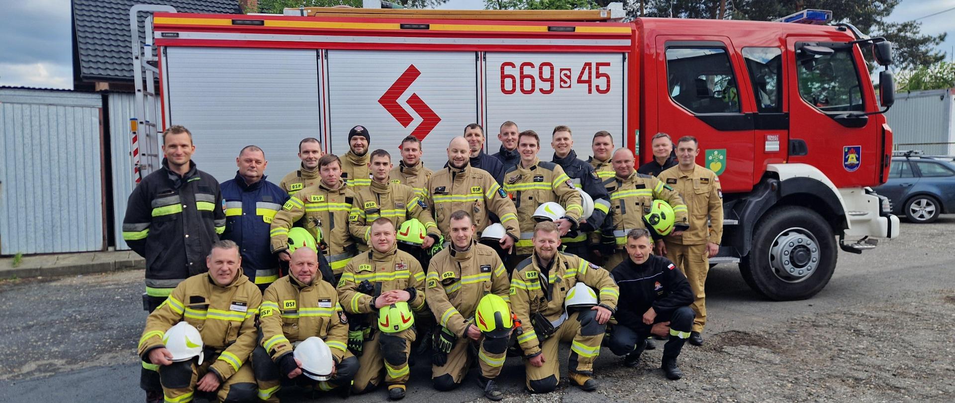 Grupowe zdjęcie strażaków uczestniczących w szkoleniu kierowców konserwatorów sprzętu ratowniczego OSP. W tle wóz strażacki.