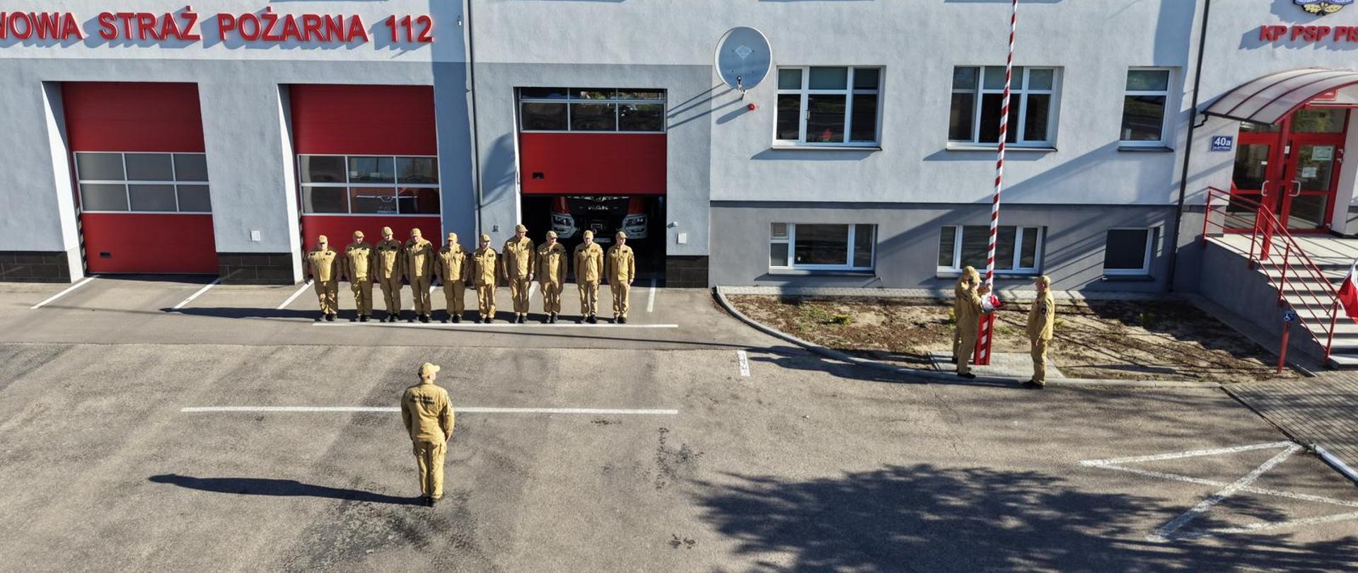 Z okazji Dnia Flagi Rzeczypospolitej Polskiej Strażacy unoszą flagę.