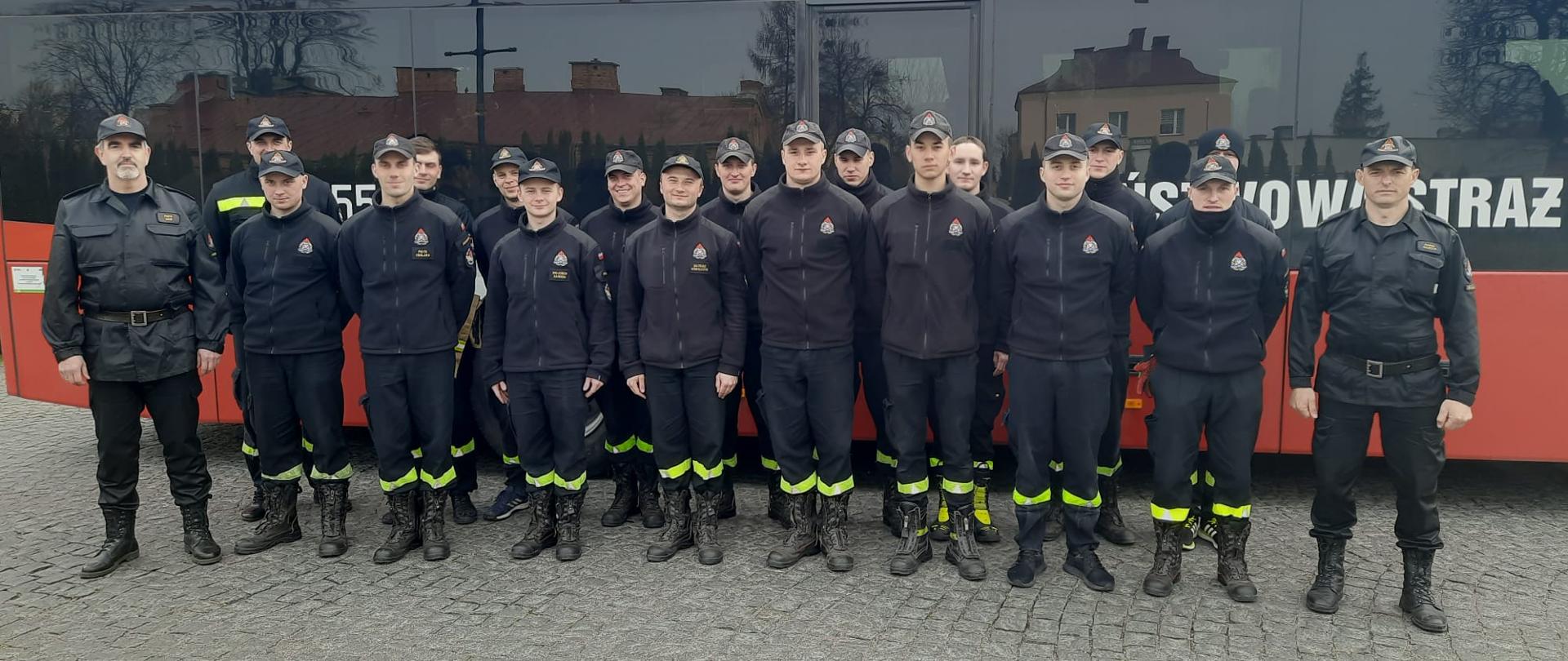 Zdjęcie grupowe kadetów Centralnej Szkoły PSP w towarzystwie dwóch dowódców na tle autokaru PSP