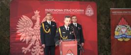 Na pierwszym planie widoczny jest mł bryg. Marcin Jasiński Komendant Powiatowy Państwowej Straży Pożarnej w Ostrowcu Św. a za nim stoją bryg. Michał Jankowski Zastępca Świętokrzyskiego Komendanta Wojewódzkiego PSP oraz bryg. Tomasz Łyjak Zastępca Komendanta Powiatowego PSP w Ostrowcu Św.