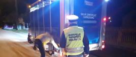Umundurowany funkcjonariusz mazowieckiej Inspekcji Transportu Drogowego stoi za pojazdem zatrzymanym do kontroli. Kierowca busa przewożącego konie stoi obok pojazdu i otwiera drzwi do przestrzeni ładunkowej.