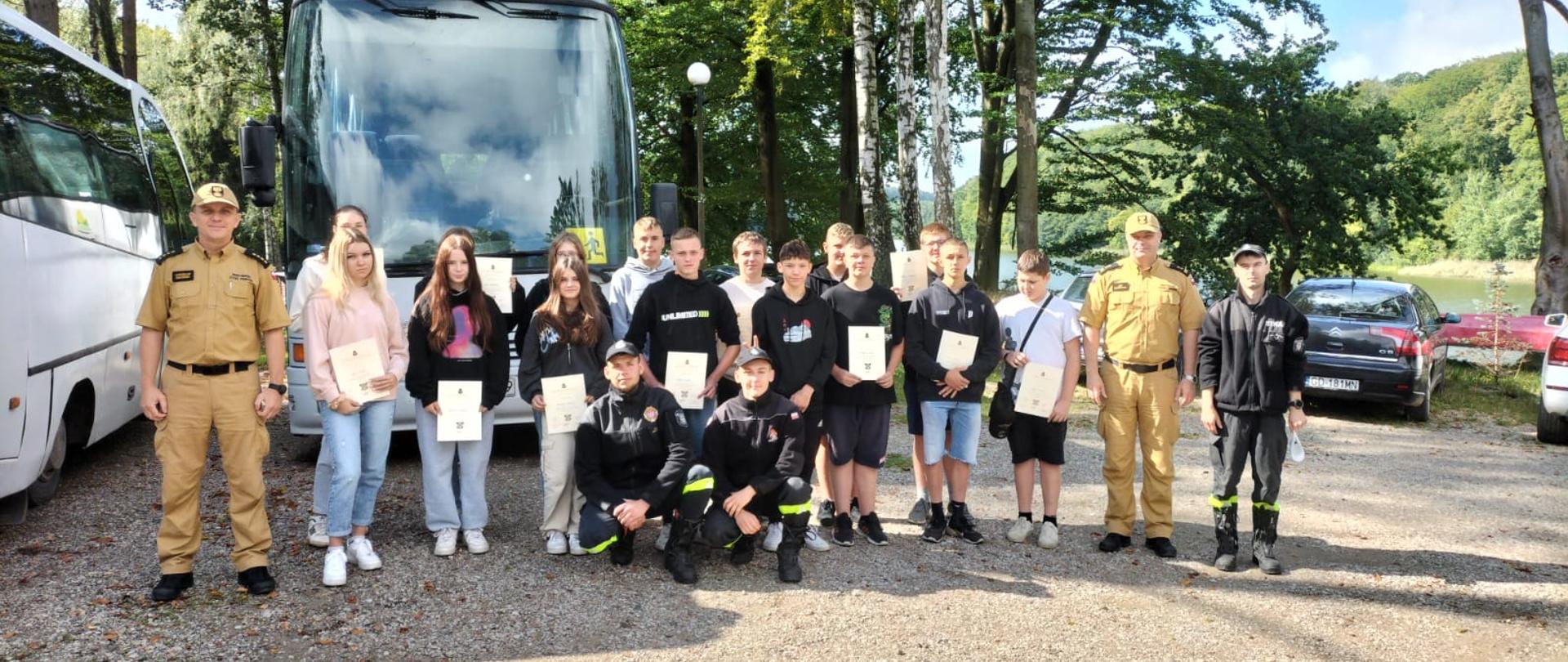 Zdjęcie przedstawia uczestników obozu wraz z komendantami z KP PSP w Pruszczu Gdańskim i strażakami z OSP Pręgowo na pamiątkowej fotografii. 