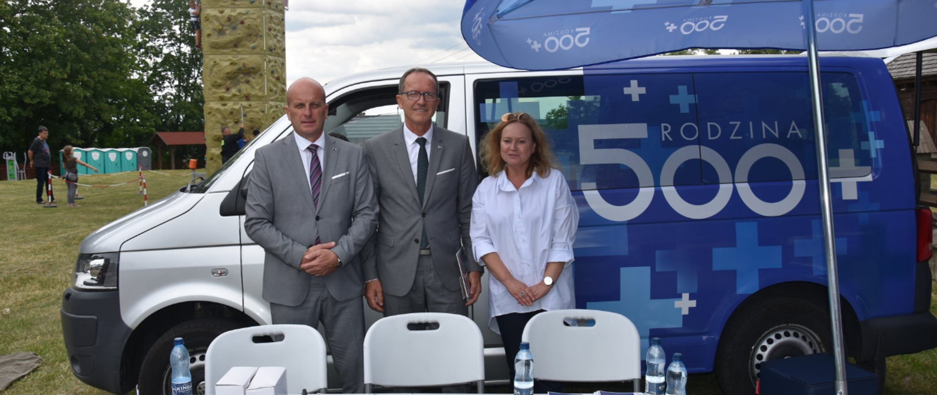 trzy osoby stojące przy aucie, na którym widać napis Rodzina 500+