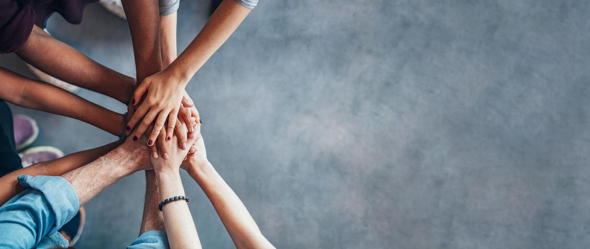 Dłonie osób jedna na drugiej.