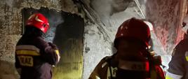 Strażacy wewnątrz budynku w pomieszczeniu