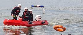 Widać strażaków na łodzi, którzy płyną ratować osobę w wodzie