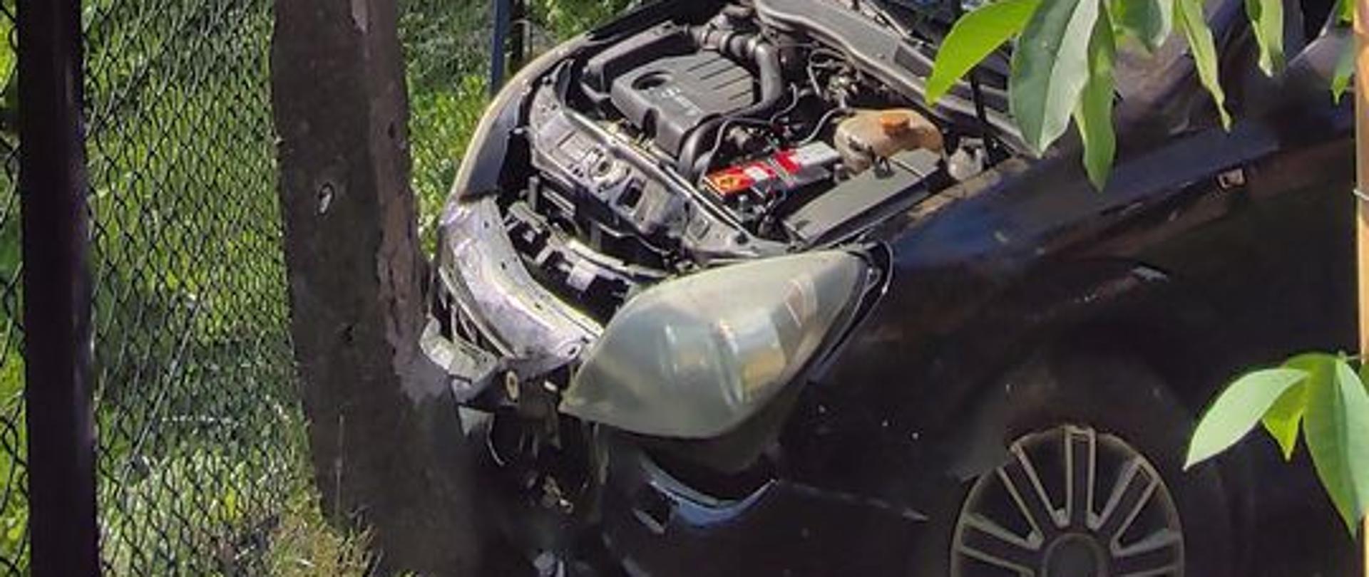 Samochód osobowy przodem przy słupie. Podniesiona klapa silnika.