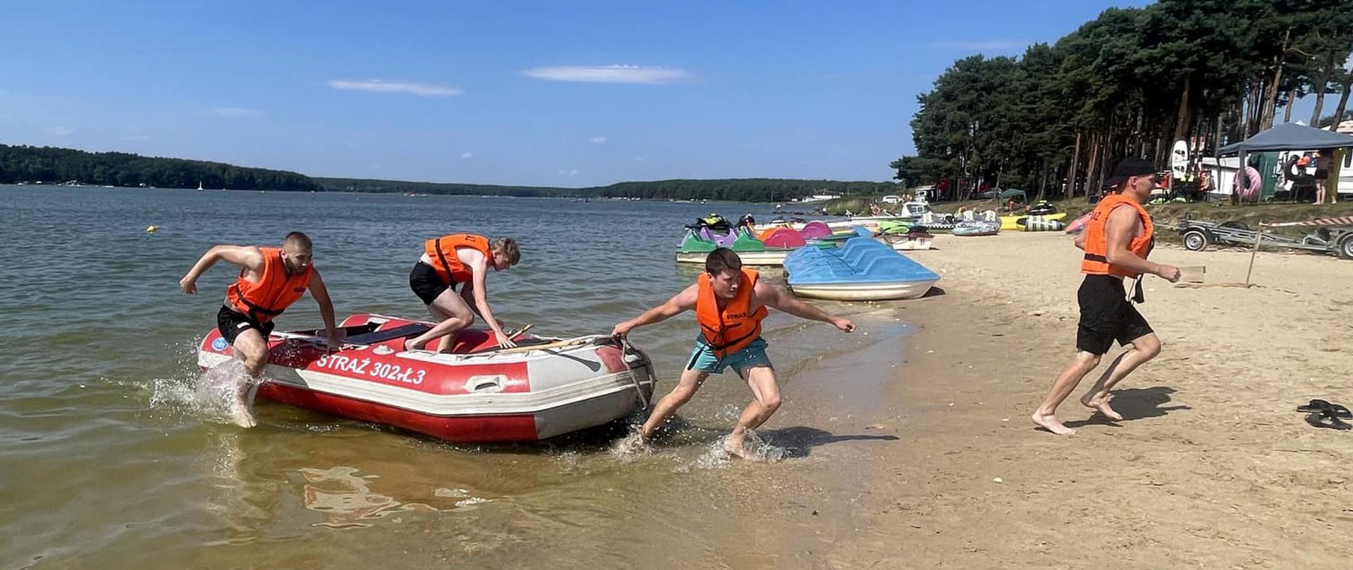 Zdjęcie przedstawia jedną z drużyn składającą się z czterech zawodników podczas konkurencji wyścig na pontonie z pagajami. Jeden z zawodników biegnie już na brzegu podczas gdy trzech wyciąga ponton z wody.
