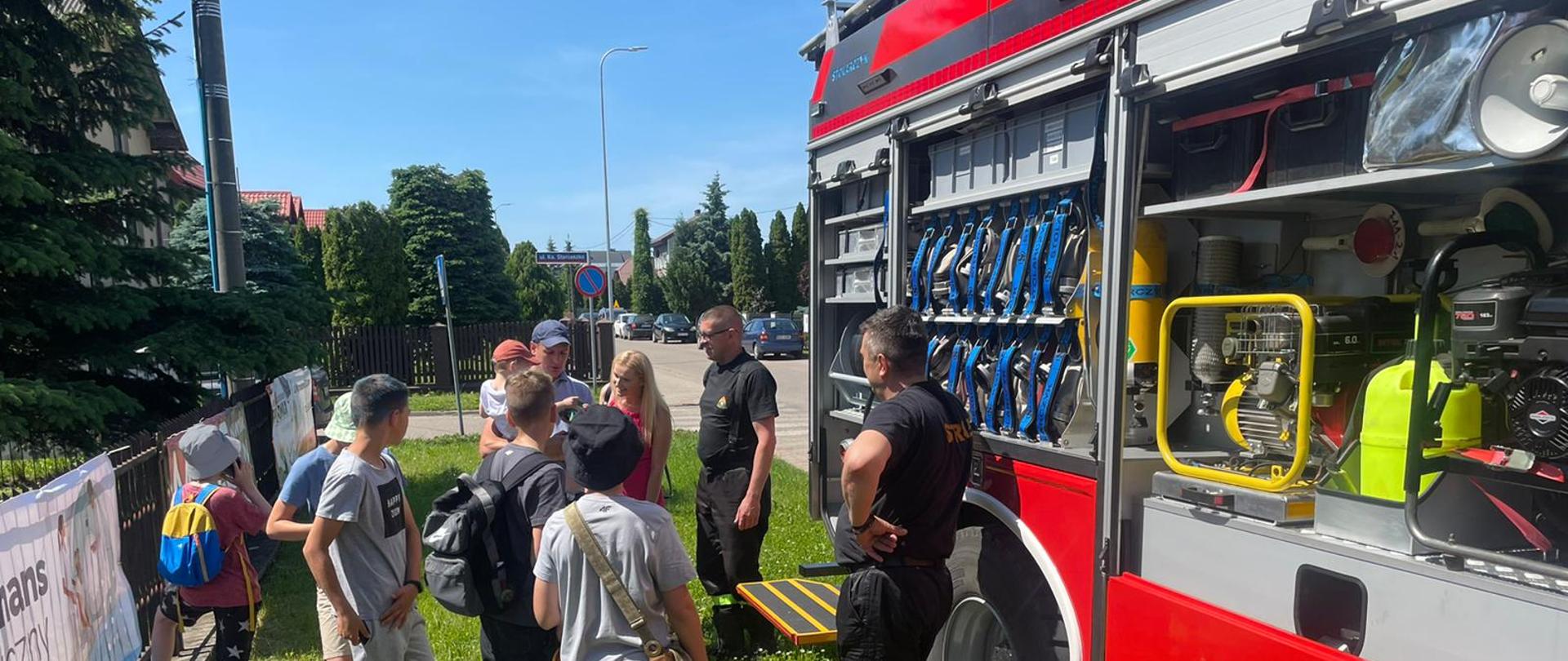 Pokaz wozów strażackich na festynie przy szkole podstawowej. Uczestnicy oglądają wóz gaśniczy.