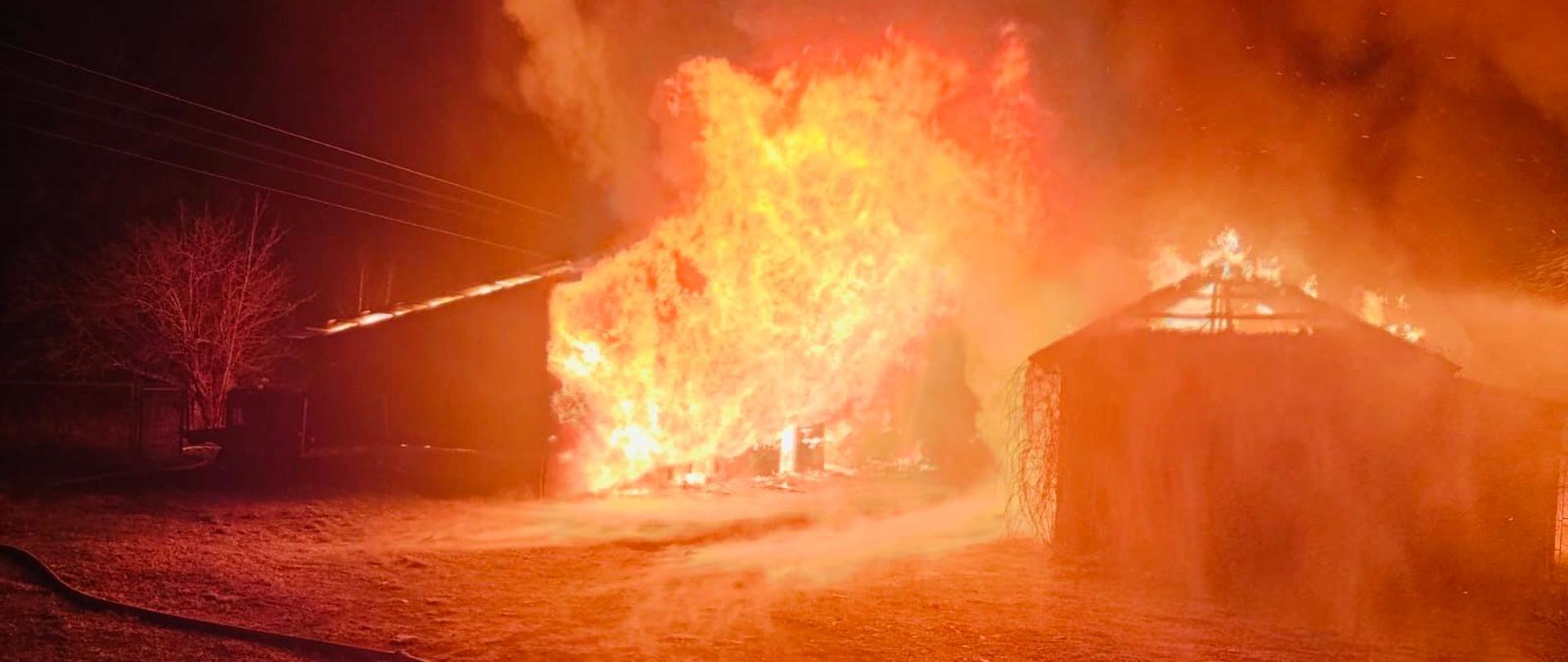 Palące się zabudowania gospodarcze, ogień wychodzący na zewnątrz.