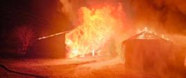 Palące się zabudowania gospodarcze, ogień wychodzący na zewnątrz.