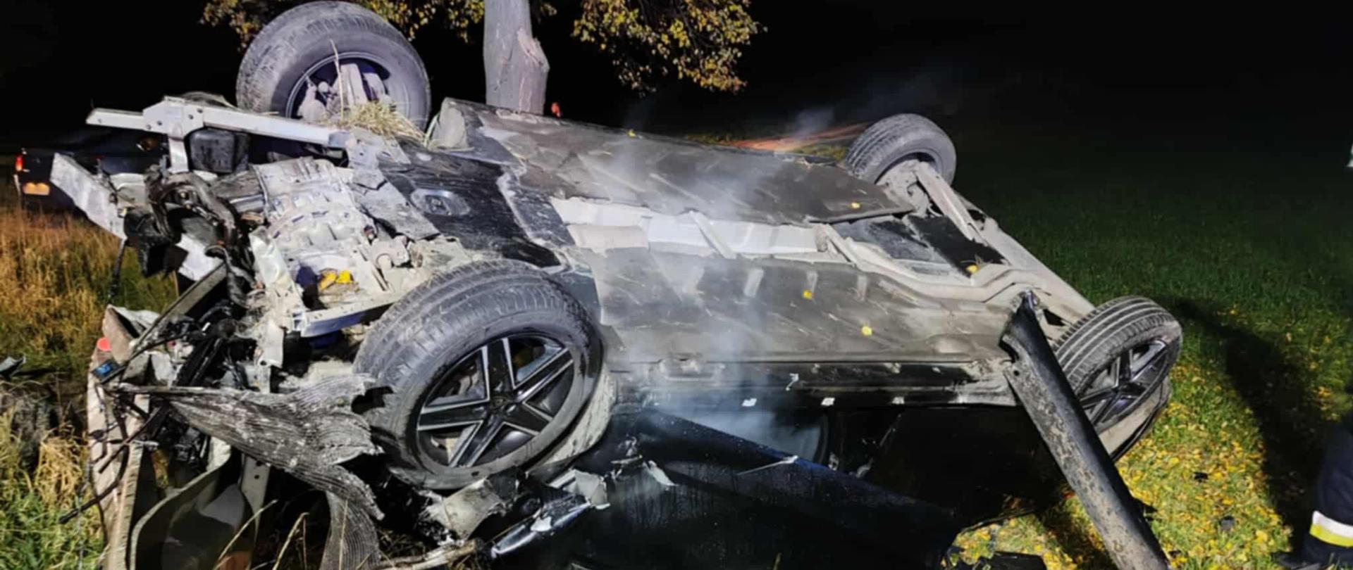 Zdjęcie przedstawia zdeformowaną bryłę pojazdu osobowego po zmroku 