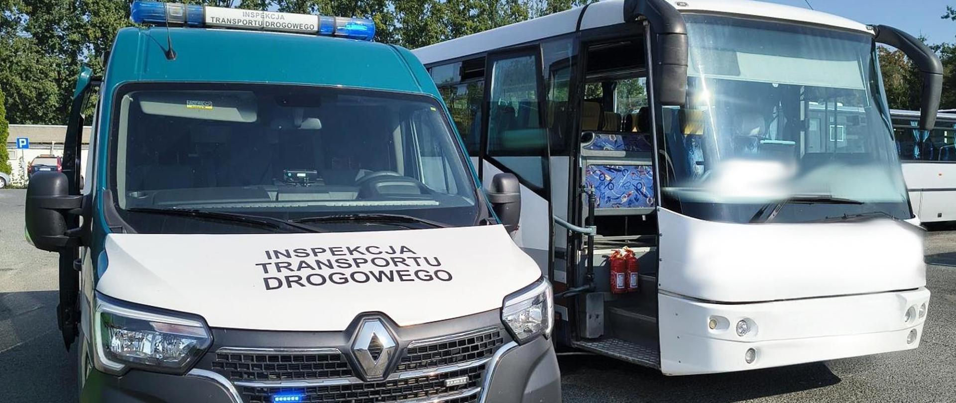 Pojazd Inspekcji Transportu Drogowego zaparkowany obok autobusu turystycznego na parkingu. Pojazd ITD ma charakterystyczne oznaczenie z napisem INSPEKCJA TRANSPORTU DROGOWEGO na masce oraz niebieskie światła ostrzegawcze na dachu. Obok stoi biały autokar z otwartymi drzwiami, przez które widać wnętrze pojazdu oraz dwie gaśnice ustawione przy wejściu. W tle znajdują się inne autobusy oraz drzewa.