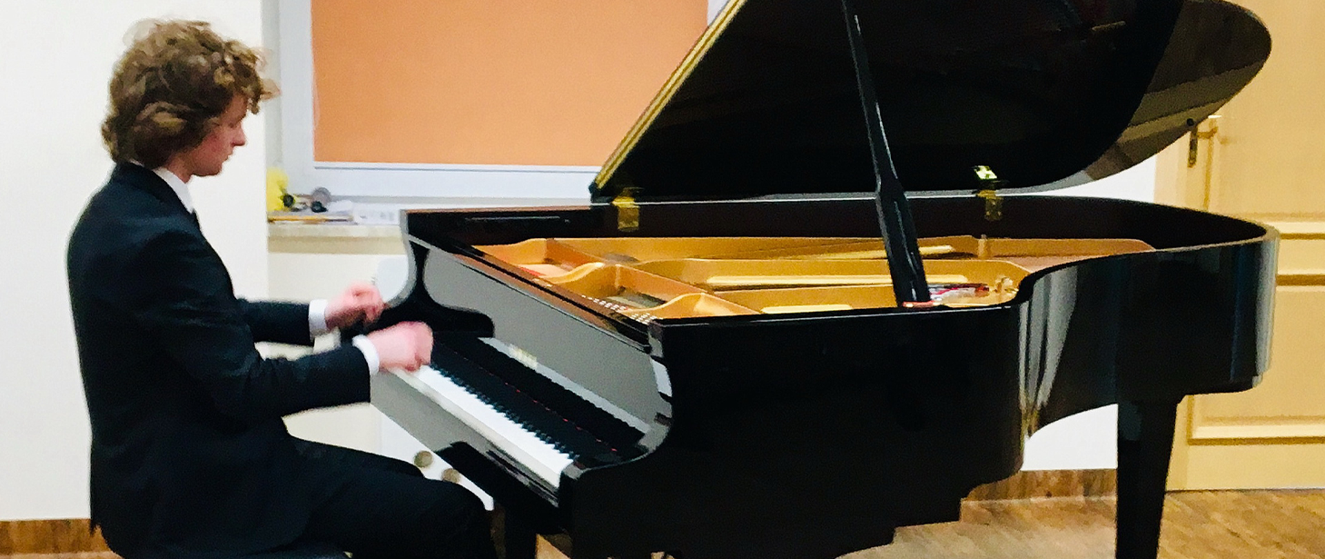 Na zdjęciu chłopiec gra na fortepianie. 