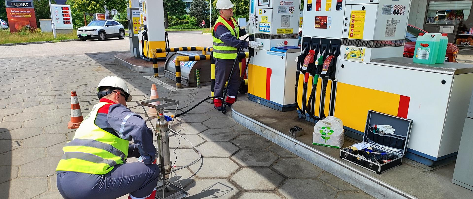 Fotografia prezentująca proces pobierania próbki kontrolnej gazu skroplonego LPG na stacji paliw przez Inspektorów Inspekcji Handlowej.