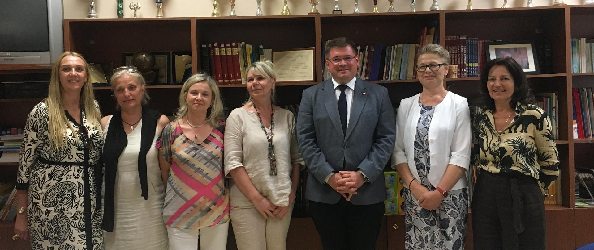 Zdjęcie zbiorowe uczestników wizyty, stoją na tle półek z książkami.