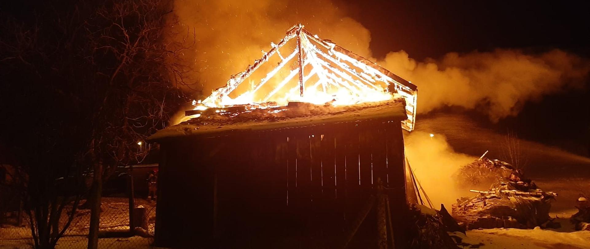 Płonący budynek gospodarczy. Płomieniami objęta jest konstrukcja dachu. na ziemi leży śnieg.