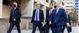 Minister rozwoju i technologii Piotr Nowak idący chodnikiem z polską delegacją podczas wizyty w Waszyngtonie, po prawej stronie idzie wicepremier i minister aktywów państwowych Jacek Sasin
