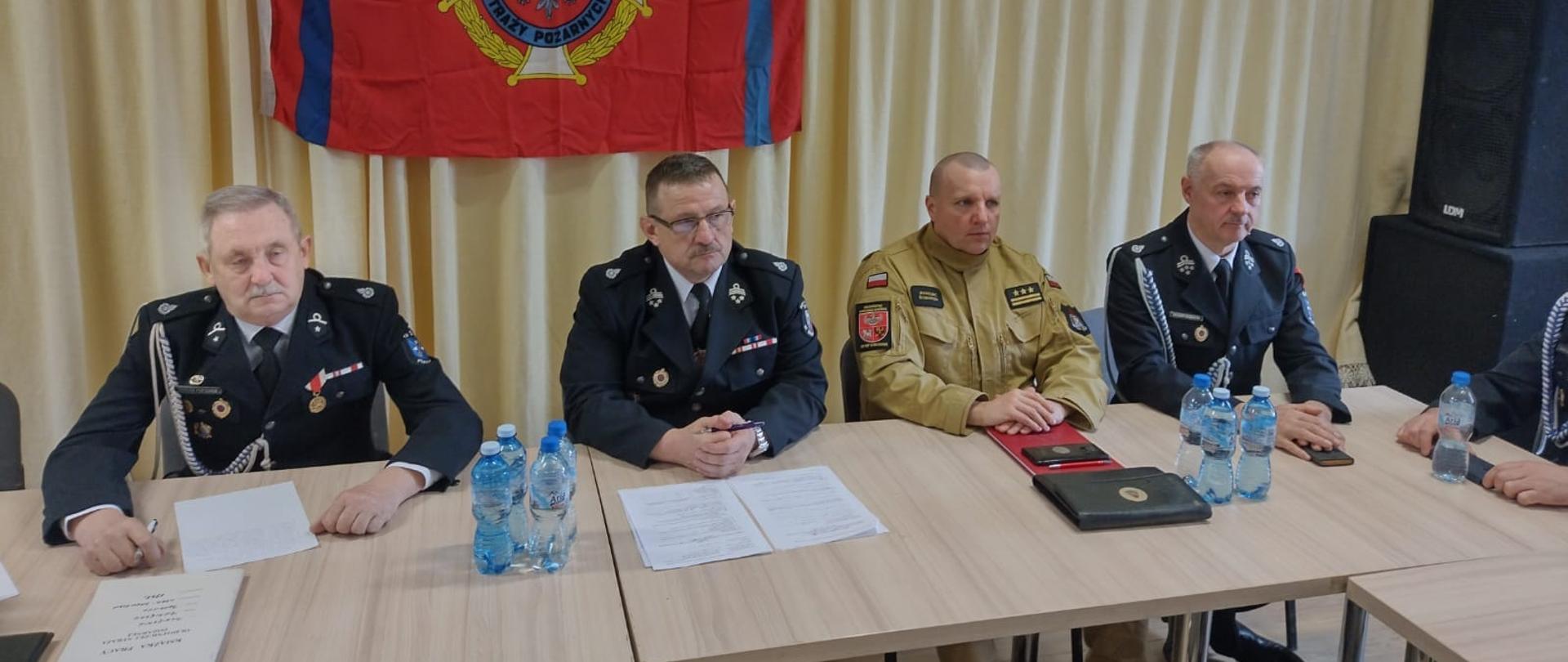 Zdjęcie zrobione na świetlicy. Za stołami siedzą strażacy w mundurach wyjściowych. Trwa zebranie.