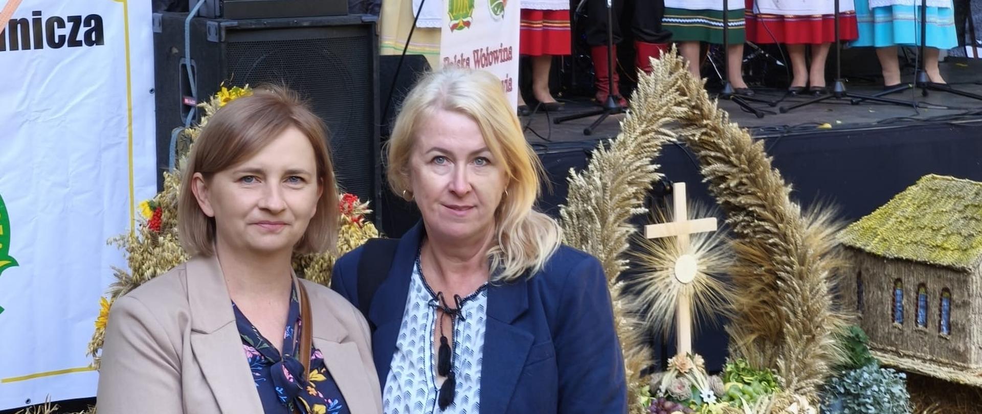 Występ zespołu ludowego na scenie. Przed sceną stojące wieńce dożynkowe oraz dwie panie inspektor z Oddziału w Oleśnicy
