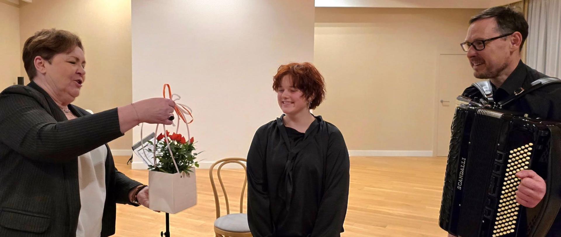 Zofia Dzienisz wraz z Ryszardem Borysionkiem otrzymują od Ewy Rocławskiej upominek po koncercie.