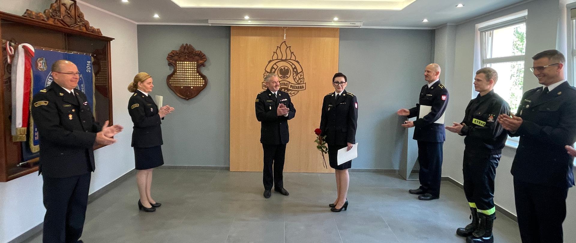 Świetlica komendy, po srodku awansowana, obok komendant. Po lewej i po prawej w szeregu stoją pozostali funkcjonariusze