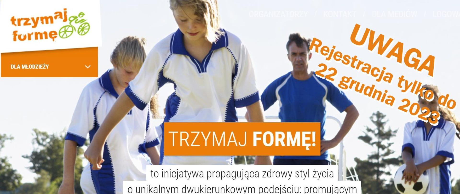 Chłopcy trenujący piłkę nożną, w tle stoi trener