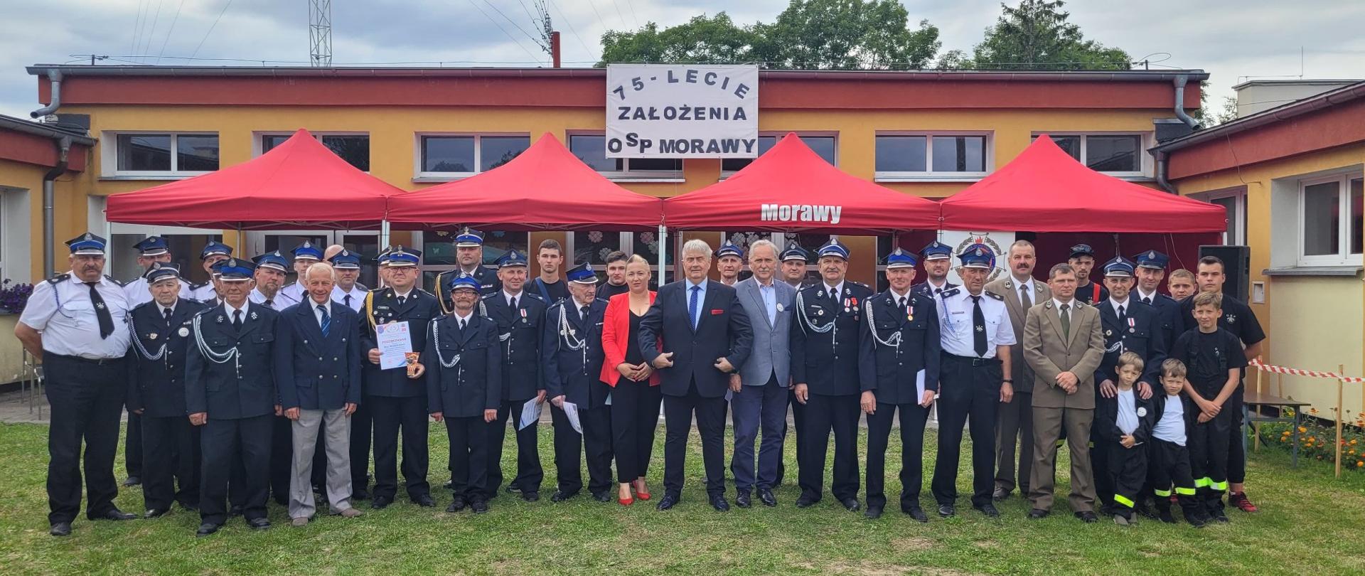 Na zdjęciu uczestnicy obchodów jubileuszu 75lecia OSP Morawy oraz zaproszeni goście stoją obok siebie na tle jednostki.
