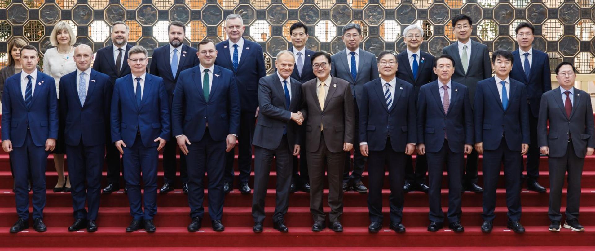 Family photo. Na zdjęciu grupa ludzi, stojących na schodach. 