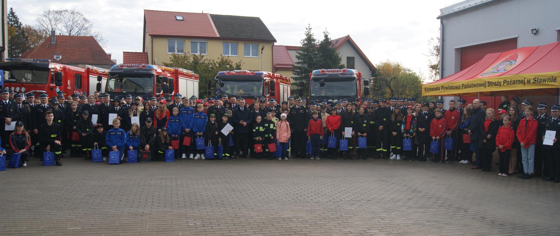 Zdjęcie zbiorowe członków OSP wraz z Młodzieżowymi Drużynami Pożarniczymi z terenu województwa zachodniopomorskiego na tle pojazdów pożarniczych
