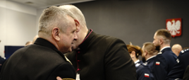Pomorski komendant wojewódzki Państwowej Straży Pożarnej składa życzenia biskupowi trzymającemu w ręce opłatek za nimi życzenia składają sobie policjanci.