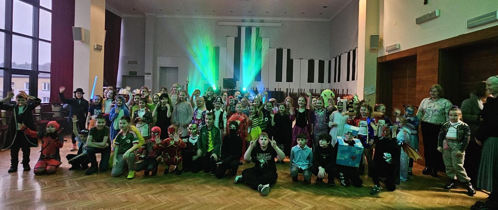 Wszystkie dzieci w różnych przebraniach stoją lub siedzą pod sceną.