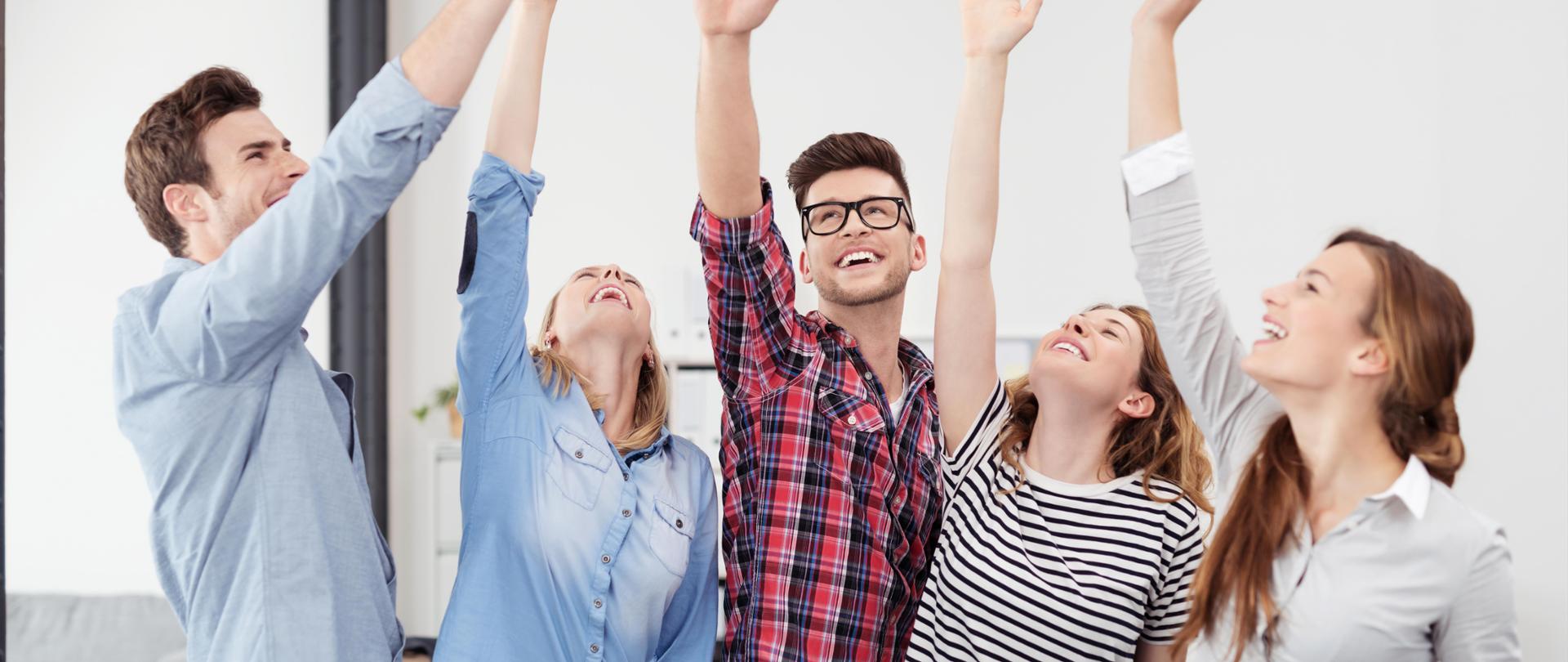 Uśmiechnięci młodzi ludzie podnoszący prawą rękę w górę